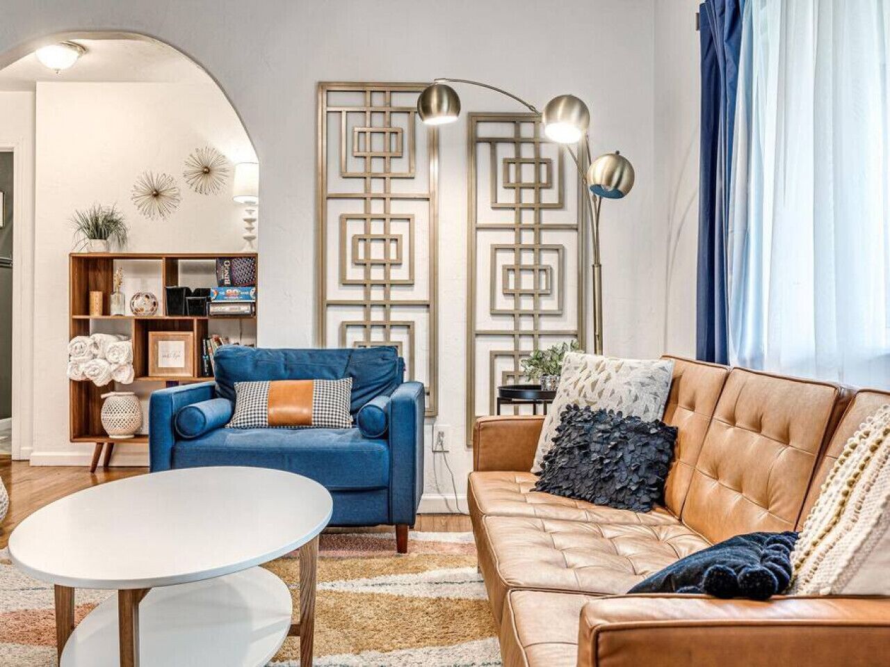 A living room with a blue sofa, a brown leather sofa, a white coffee table, and a decorative wall panel.