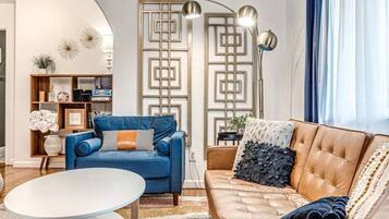 A living room with a blue sofa, a brown leather sofa, a white coffee table, and a decorative wall panel.