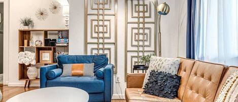 A living room with a blue sofa, a brown leather sofa, a white coffee table, and a decorative wall panel.