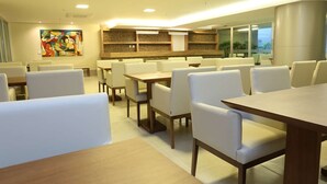 Ein Hotel-Essbereich mit mehreren Tischen und Stühlen, einem farbenfrohen abstrakten Gemälde an der Wand und einem modernen Interieur.
