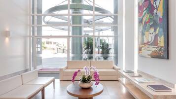 Un lobby moderno con un sofá, un banco y una mesa redonda con orquídeas.