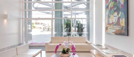 Een moderne lobby met een bank, een zitbank en een ronde tafel met orchideeën.