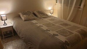 Una camera da letto con un letto, due lampade da comodino, un comodino e una finestra con tende.