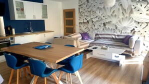 Un soggiorno moderno con un tavolo da pranzo in legno, sedie blu, un divano e un tavolino bianco.