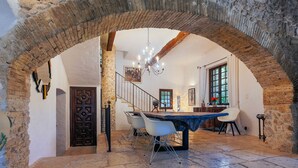 A dining area with a stone archway, a chandelier, and a table set for two. - The Moulin de Boursac - Historic renovated Mill with a huge pool (Vence)