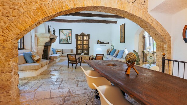 A rustic interior with a stone archway, a wooden dining table, and a cozy seating area with cushions and a sofa. - The Moulin de Boursac - Historic renovated Mill with a huge pool (Vence)