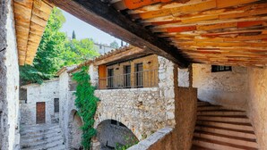 A stone staircase leading to a wooden balcony with a stone wall and a window. - The Moulin de Boursac - Historic renovated Mill with a huge pool (Vence)