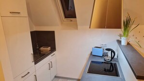 A modern kitchen with white cabinets, a black countertop, a built-in stove, and a toaster.