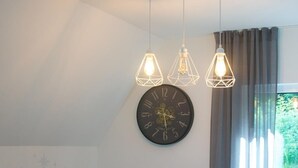 A dining area with a table, chairs, a clock, and pendant lights.