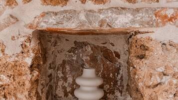 Un mur de pierre comportant une niche dans laquelle se trouve un objet cylindrique blanc, à surface striée.