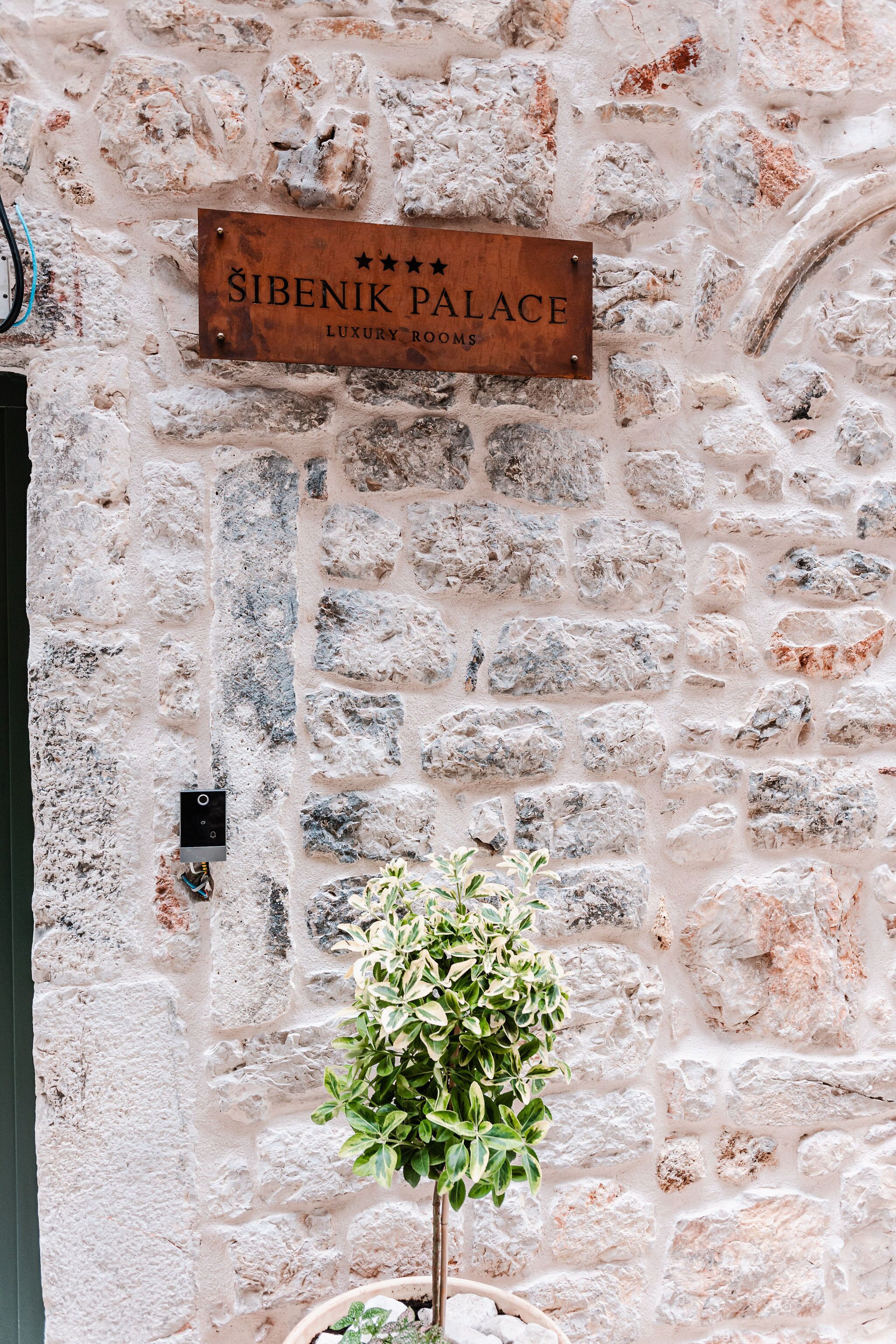 A stone wall with a sign reading "Sibenik Palace Luxury Rooms."