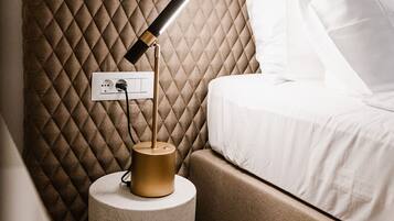 Een moderne slaapkamer met een gewatteerd hoofdeinde, een bedlampje en een wit bed.