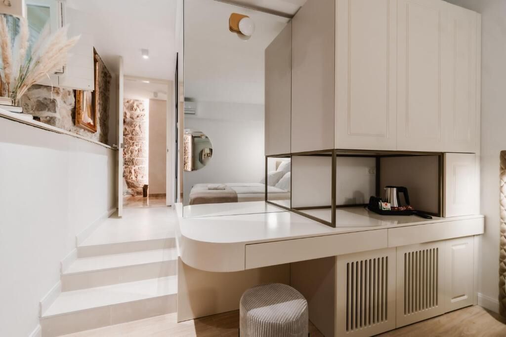 A modern bedroom with a built-in wardrobe, a bedside table with a lamp, and a view of the adjacent bathroom.