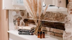 A kitchen with white cabinets, a stone wall, and a countertop with books and bottles. - Šibenik Palace (Sibenik)