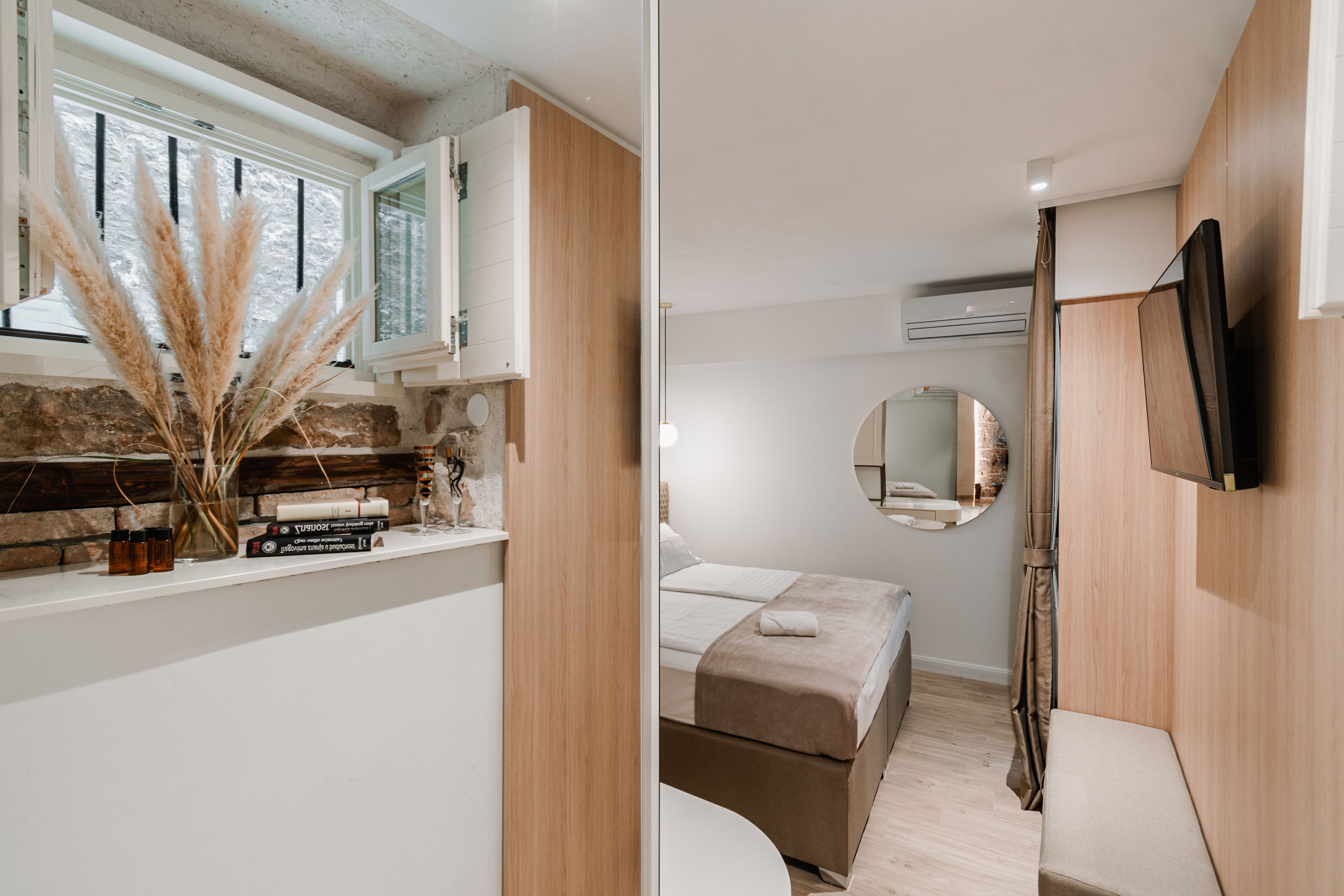 Een moderne slaapkamer met een bed, nachtkastje en spiegel.