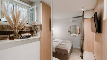 Een moderne slaapkamer met een bed, nachtkastje en spiegel.