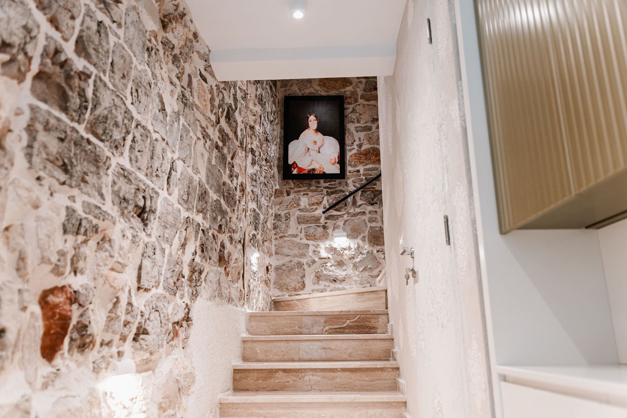A stone staircase leading to a room with a framed artwork on the wall.