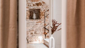 A room with a stone wall, a white door, a round table with a black base, and a woven rug. - Šibenik Palace (Sibenik)