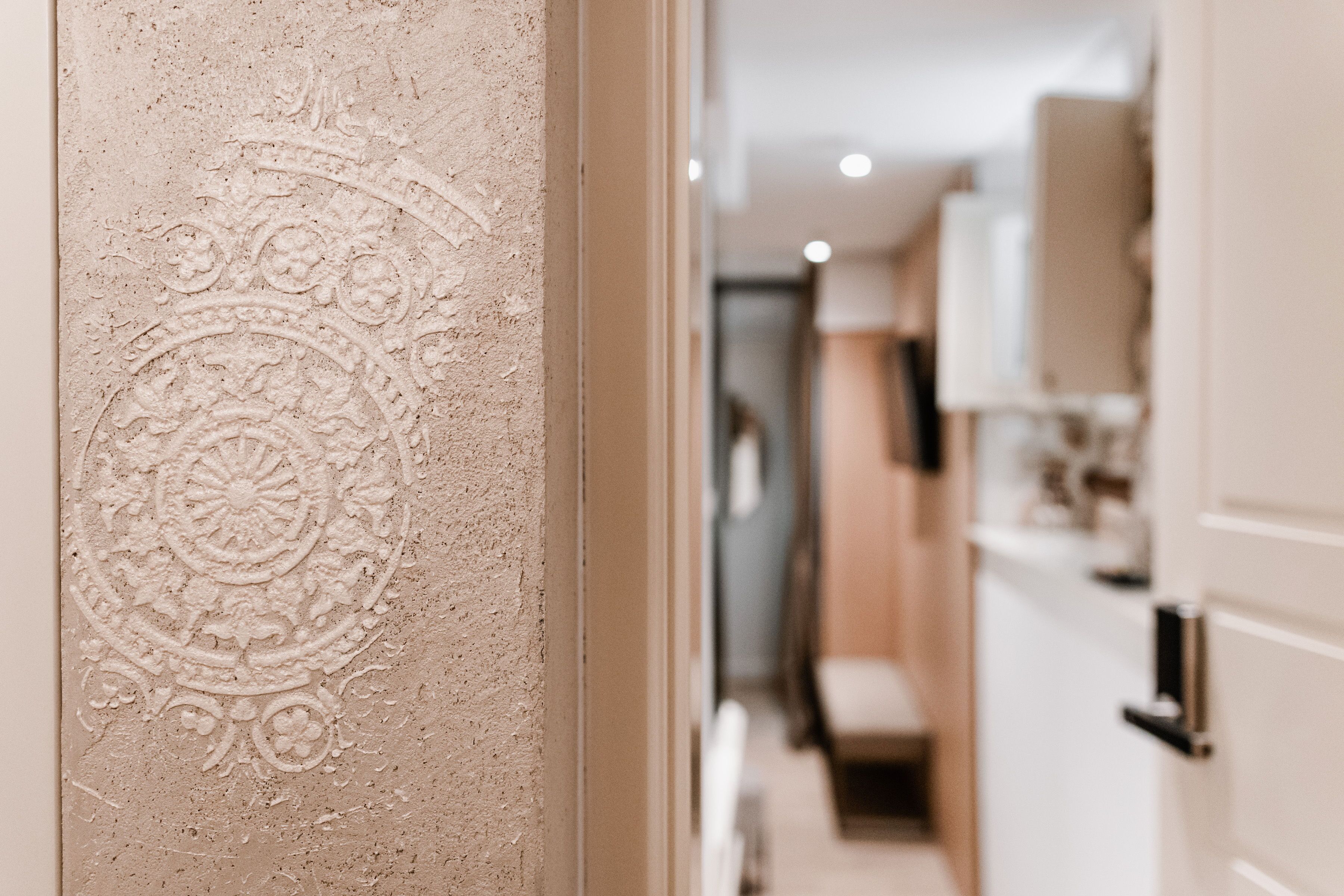 A hallway with a textured wall and a door leading to a room.