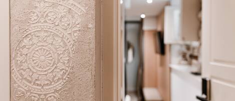 Un pasillo con una pared texturizada y una puerta que da a una habitación.