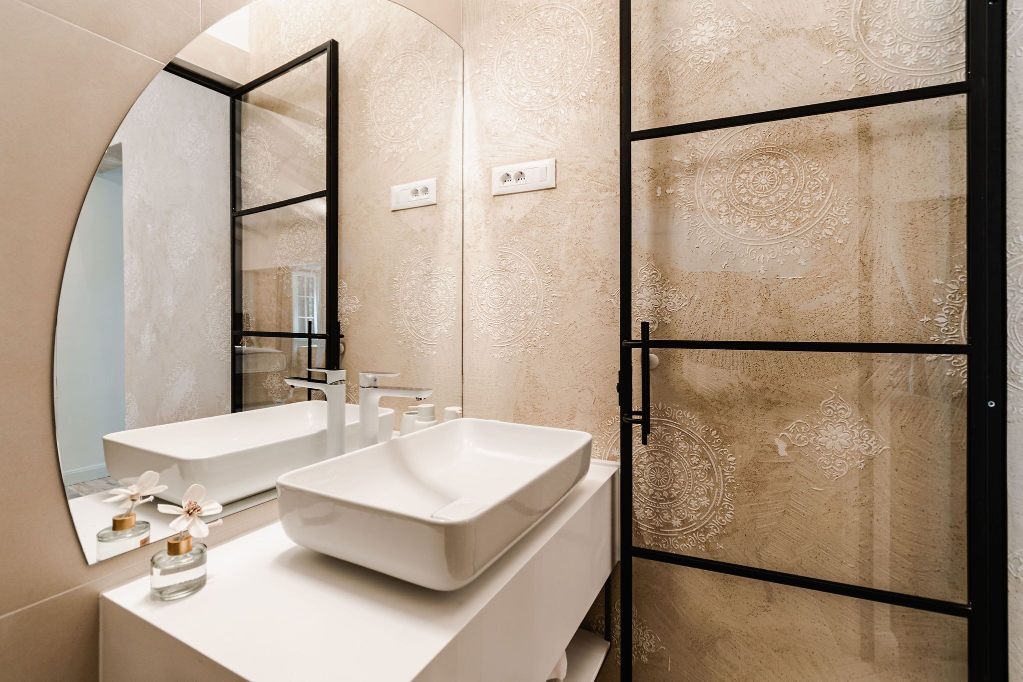 A modern bathroom with two sinks, a large mirror, and decorative wall panels.