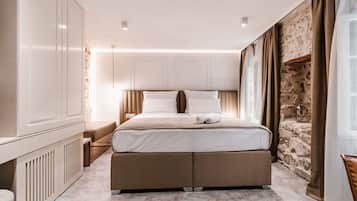 Een moderne slaapkamer met een groot bed, een inbouwkast, een accentmuur van steen en een knus zithoekje.