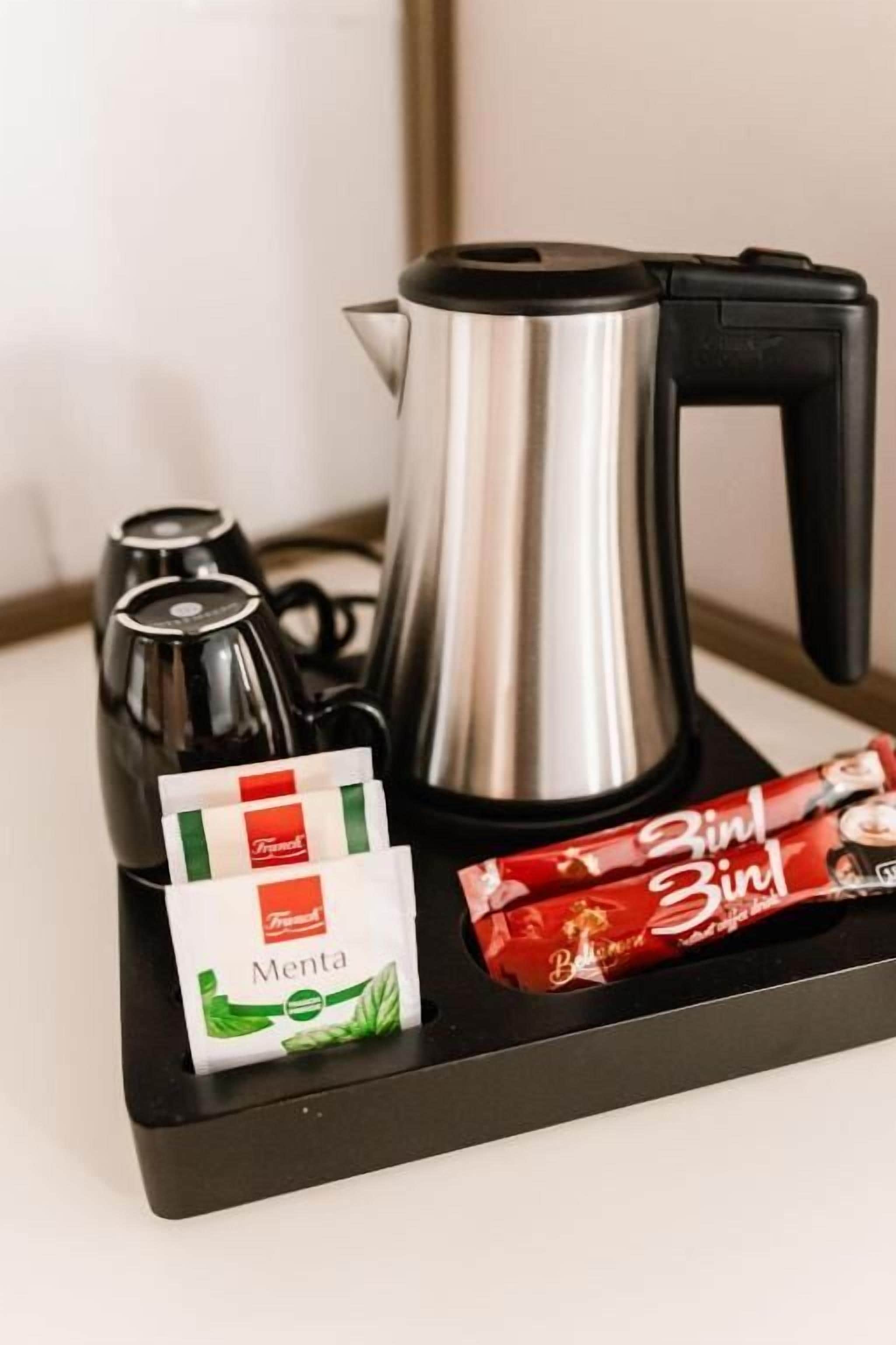 A coffee maker, a kettle, and two packets of Menta and Zintl chocolate on a tray.