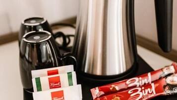 A coffee maker, a kettle, and two packets of Menta and Zintl chocolate on a tray.