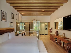 A bedroom with a large bed, a wooden ceiling, a bathroom with a glass door, and a dining area with a table and chairs. - Live Aqua San Miguel de Allende (San Miguel de Allende)