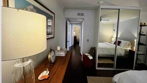 Una camera d'hotel con un letto, un comodino con lampada, una sveglia e uno specchio.