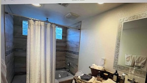 Un bagno con tenda da doccia, vasca, water, lavandino e specchio.