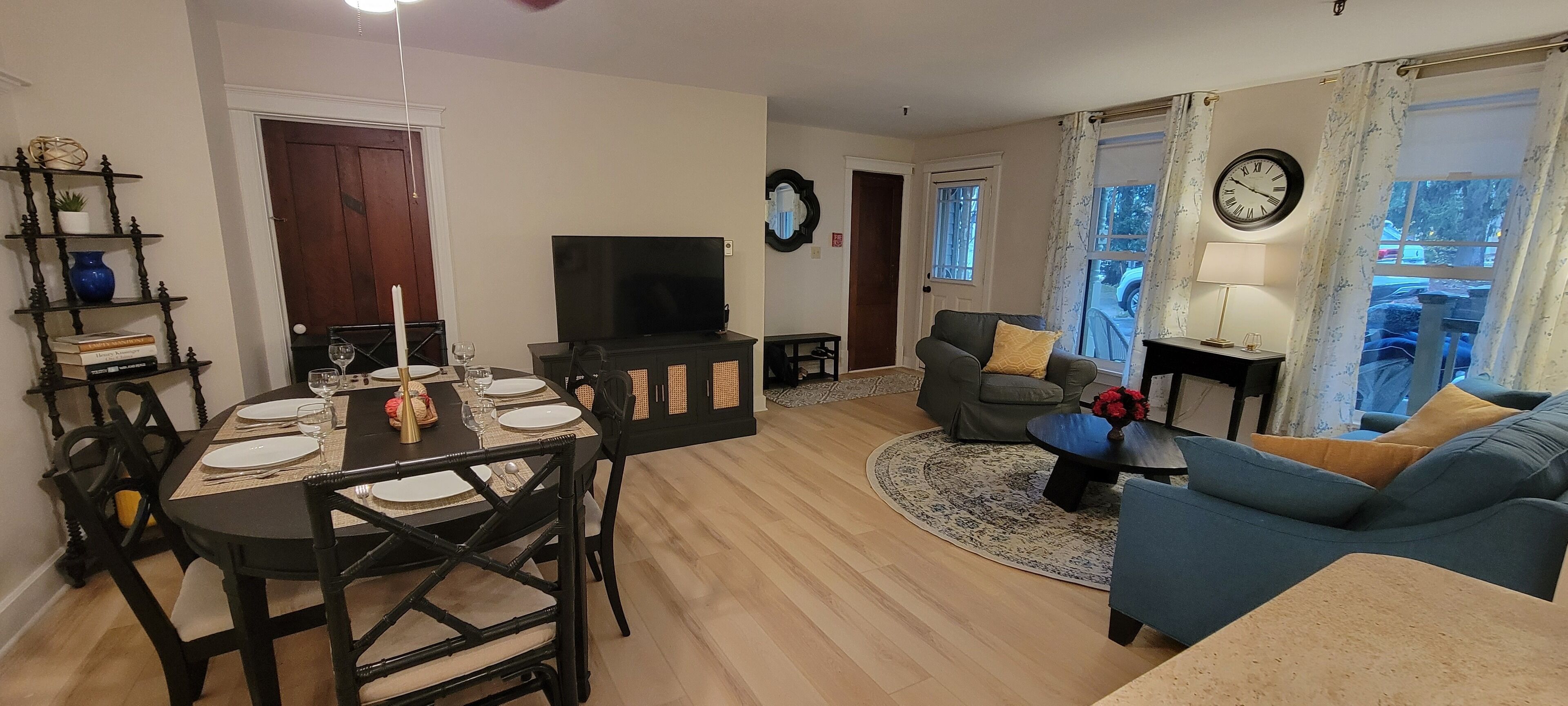 A living room with a TV, a dining table set for four, a sofa, and a chair.