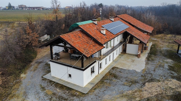 A two-story house with a red-tiled roof, a balcony, and solar panels.