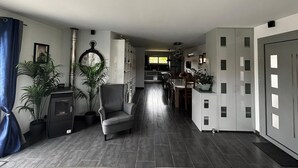 Un salon moderne avec un fauteuil gris, une plante en pot et une horloge au mur.