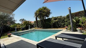 Une piscine avec des chaises longues et un espace ombragé.