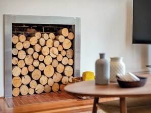 Una habitación con chimenea, una mesa redonda de madera y suelo de baldosas.