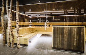 A modern sauna with wooden benches and birch trees, labeled 'Finnische Sauna 90°'.