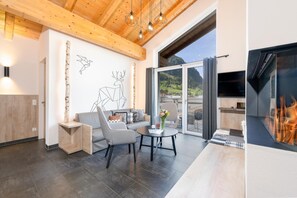 A modern living room with a wooden ceiling, a large window, a fireplace, and a wall art piece.