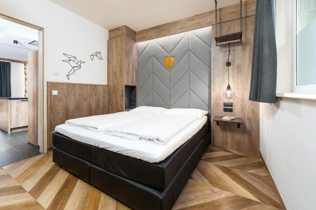 Un dormitorio moderno con cama, suelo de madera, cabecero con diseño geométrico y decoración en la pared.