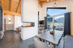 A modern kitchen with a large window, a dining area with a wooden table, and a fireplace.