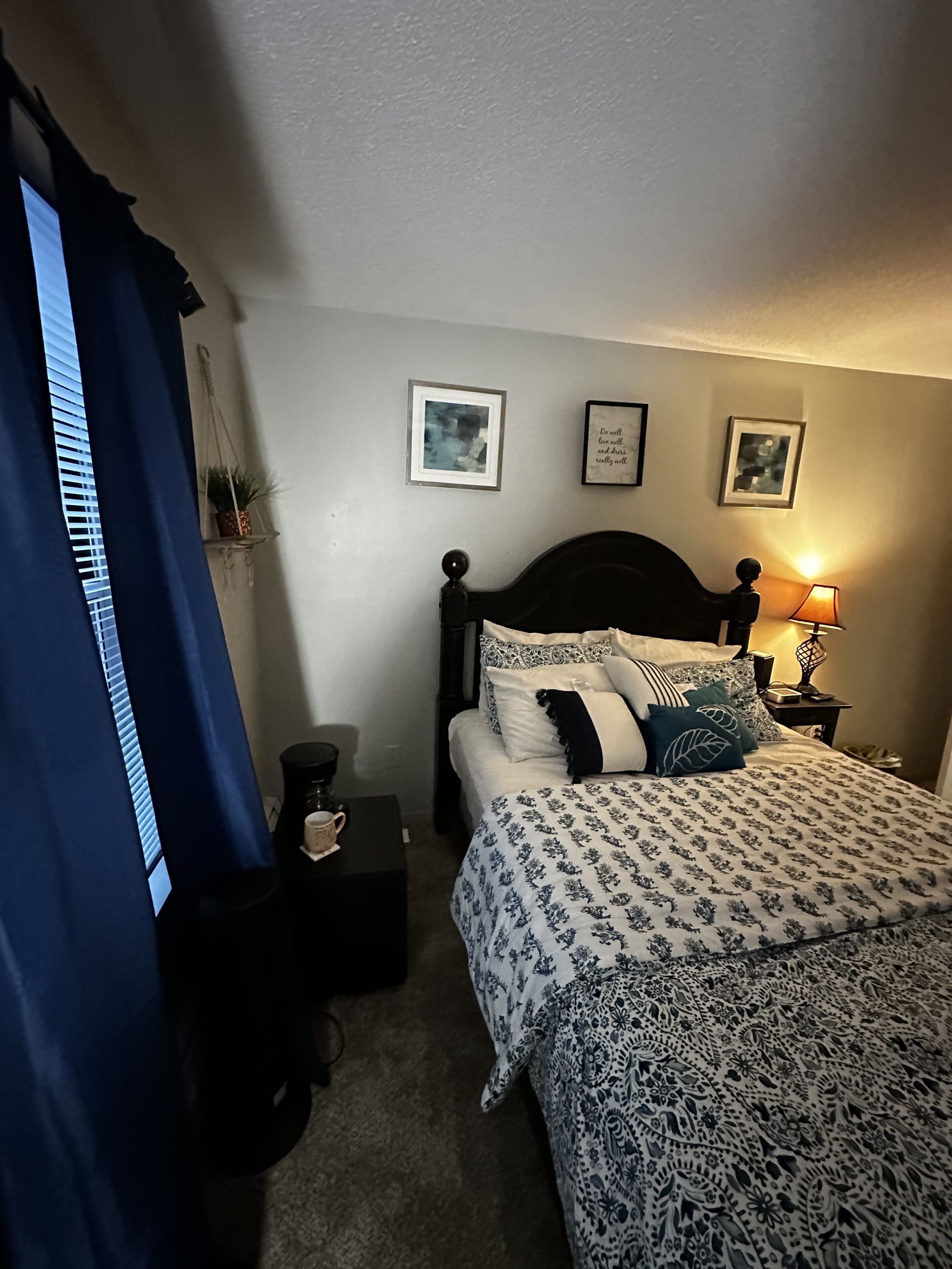 A bedroom with a bed, bedside tables, a coffee maker, and wall art.