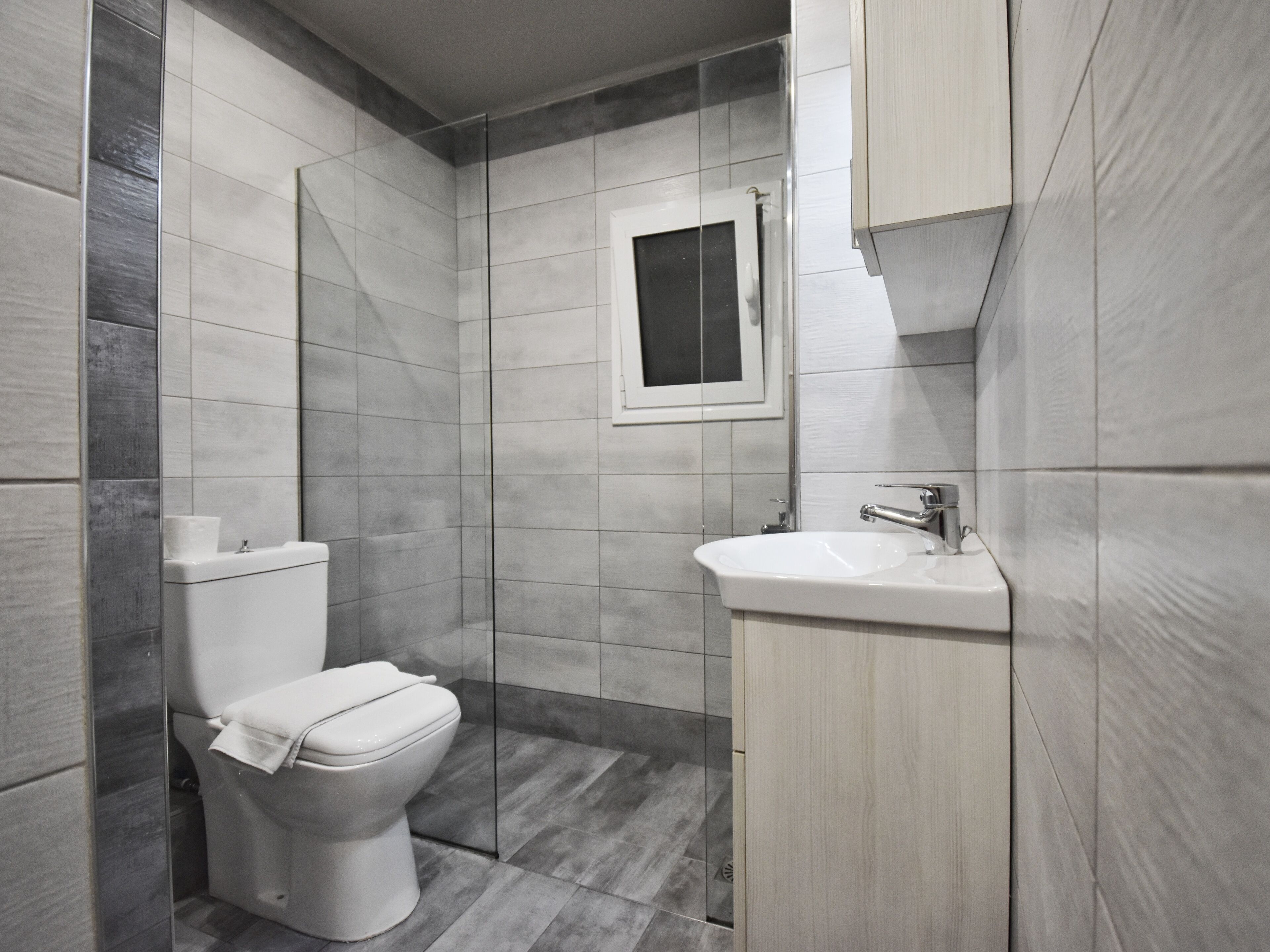 Un baño moderno con inodoro, lavamanos y cabina de ducha de vidrio.