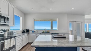 A modern kitchen with a large island, white cabinetry, and a view of the ocean. - Perfect, beachfront pet friendly 5 bedroom home, close to waters (Gulf Shores)