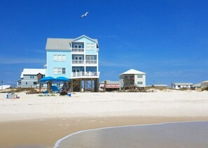 Una propiedad frente al mar con un edificio de varios pisos, una zona de playa techada y una playa de arena.