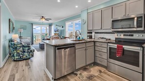 A modern kitchen with stainless steel appliances, a central island, and a view to the outside. - Beachfront Bliss Ocean Pier 4 Oceanfront 2 bed 2 bath Windy Hill (North Myrtle Beach)