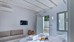 A modern bedroom with a bed, a sofa, a TV, and a window. - Fully equiped, spacious cozy apartment (Paros)