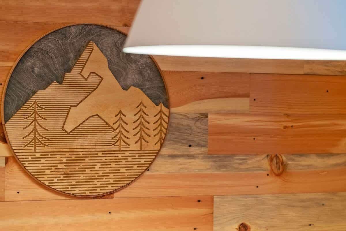 Un mur en bois orné d’une découpe circulaire représentant un paysage de montagne et d’arbres.