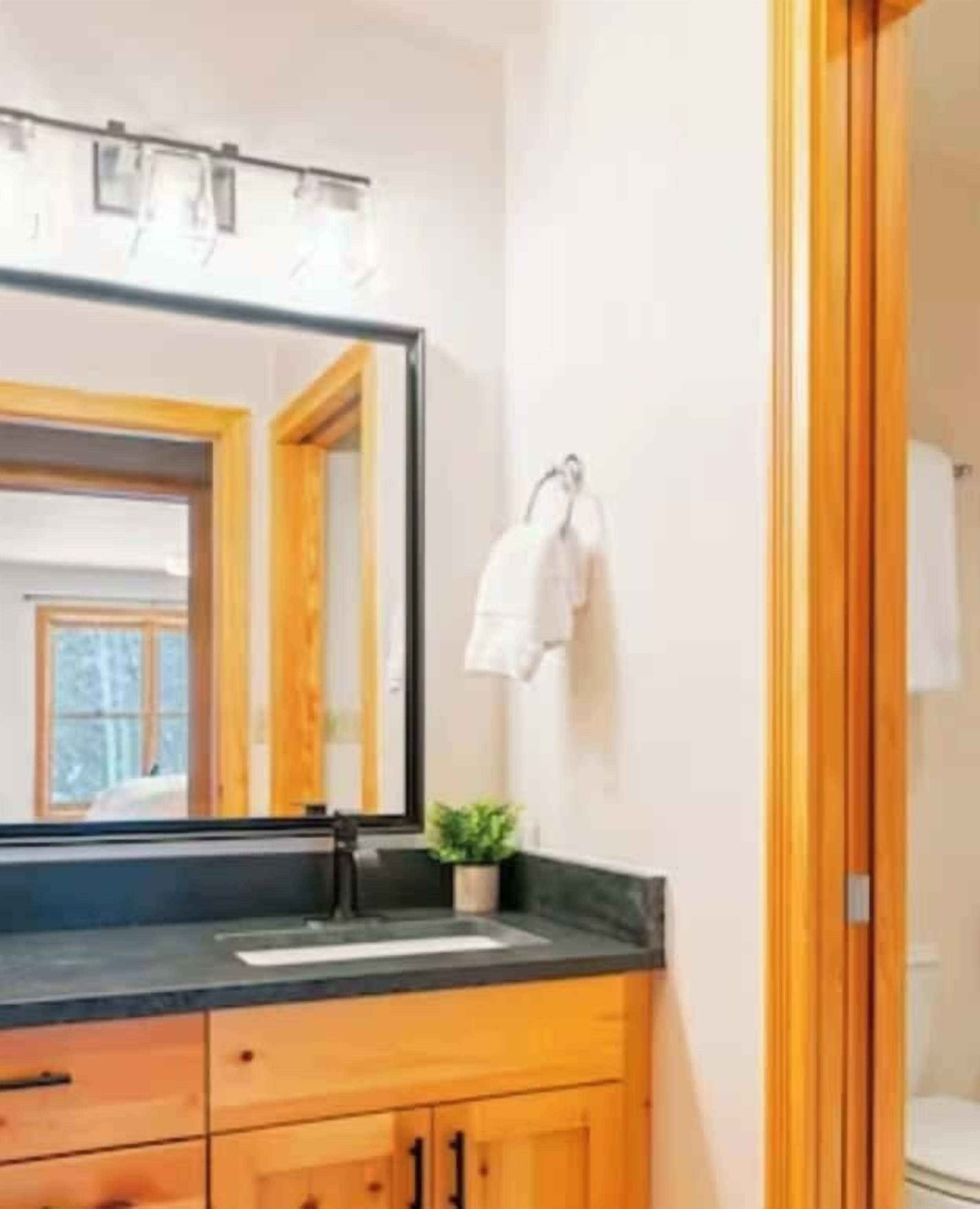Une salle de bain avec un grand miroir, un lavabo, des meubles en bois et un porte-serviettes.