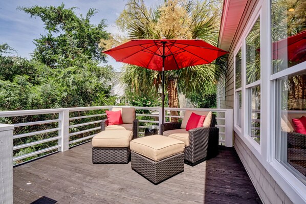A covered outdoor seating area with wicker furniture and a red umbrella. - Relaxing Zen House! Work, relax, & play two blocks from private beach access! (Kure Beach)