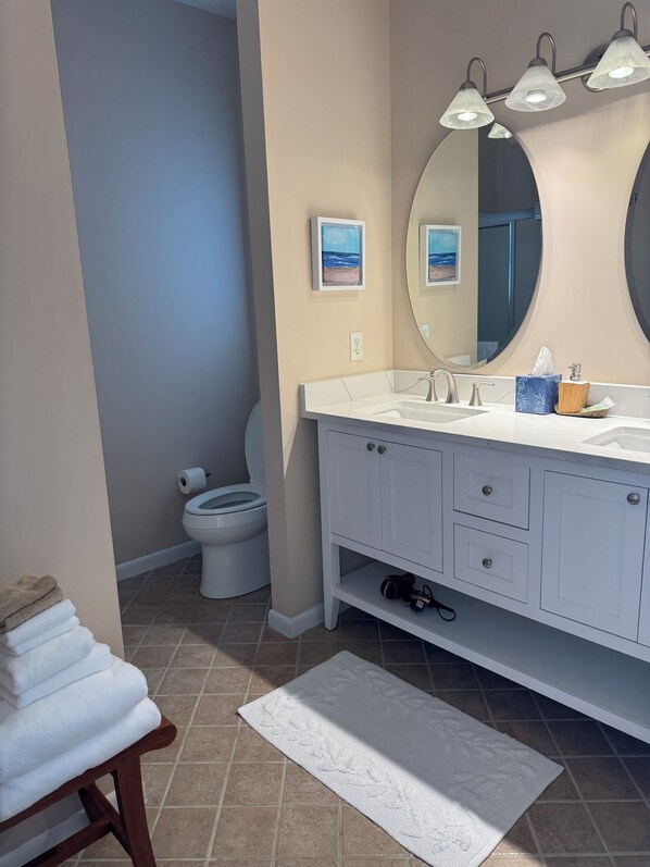 A bathroom with a white vanity, a large mirror, and a toilet.
